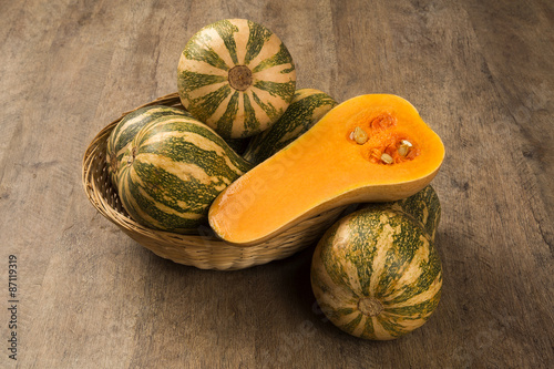 Some Paulistan pumpkins in a basket over a wooden surface on a p photo