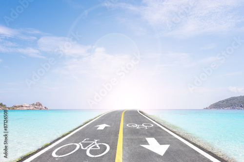Bike lane and sea beach against blue sky.