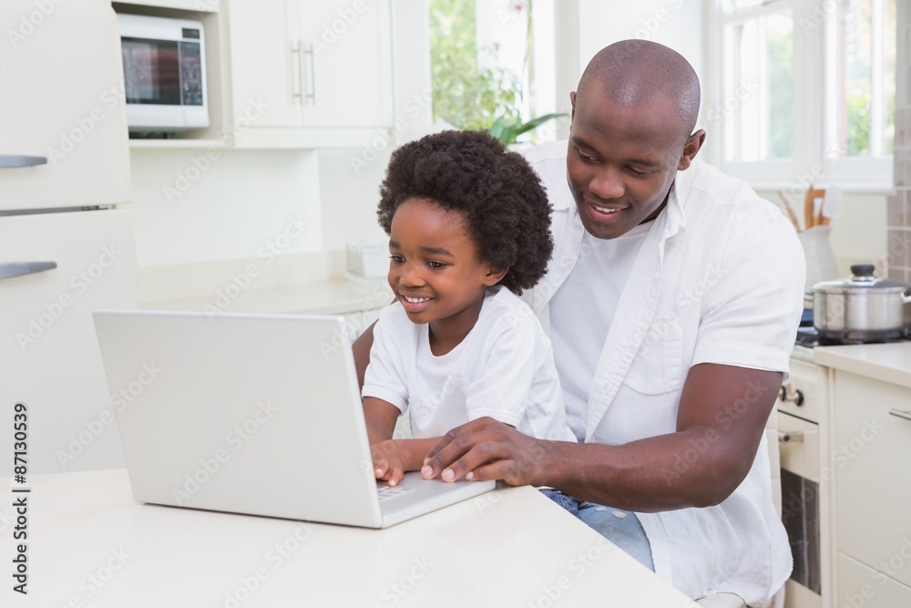 Father and son using laptop on the couch Father and son using laptop on the couch