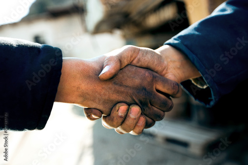 Handshake two workers men at industry close up.