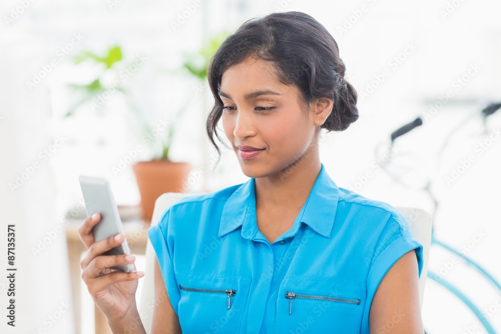 Casual businesswoman text messaging in office Casual businesswoman text messaging in office