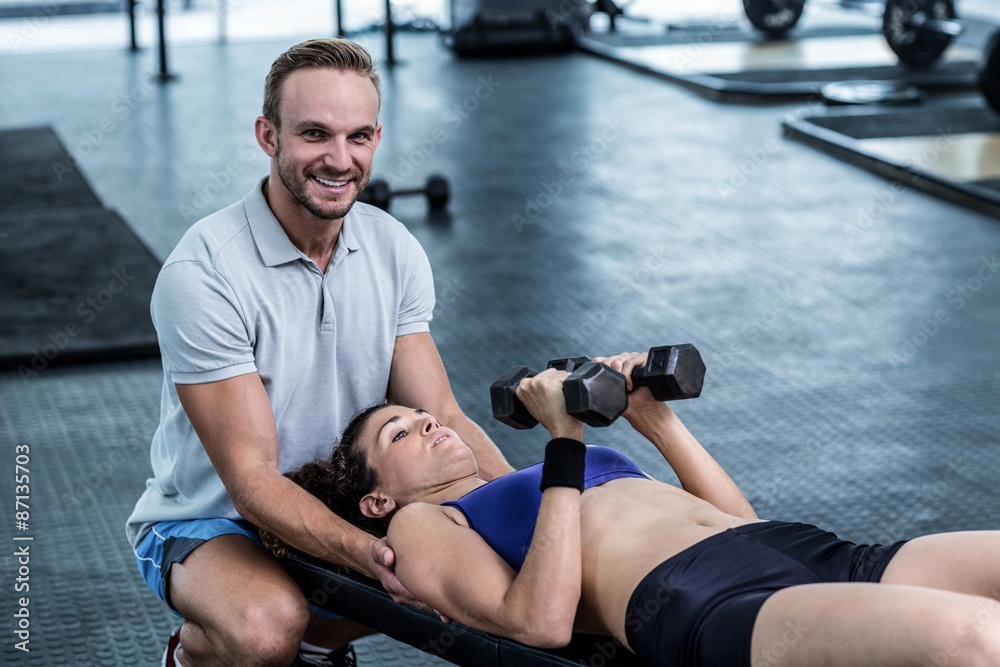 A muscular woman about to lift dumbbells