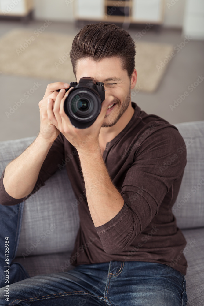mann sitzt auf dem sofa und fotografiert mit seiner dslr