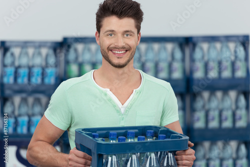 mann kauft eine kiste wasser im supermarkt photo