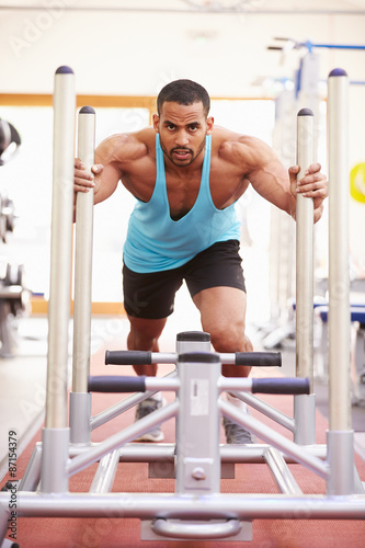 Muscular man working out using equipment at a gym, vertical