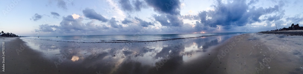 Panoramic view of sky reflection in the ocean shore at sunrise 