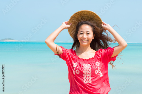 沖縄の美しい海をバックに麦わら帽子をかぶる女性(1)