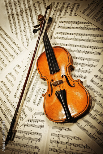 Old wood violin lying on musical notes