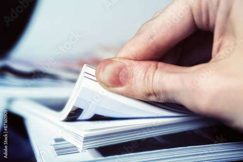 Man's hand turned over a stack of magazines