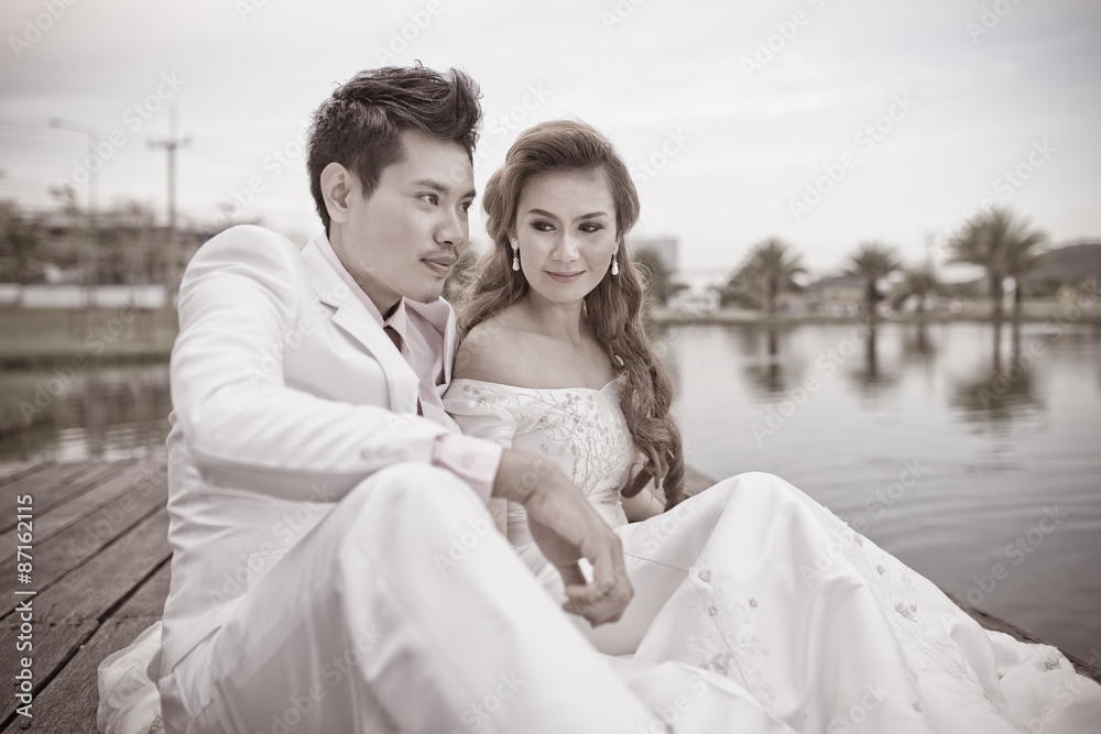 Bride and groom sitting on the edge of the river bridge Bride and groom sitting on the edge of the river bridge