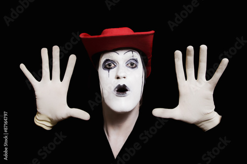 face and hands of mime with dark make-up in red hat photo