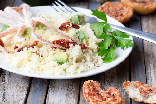 Couscous with seafood, dried tomatoes, avocado and little toast