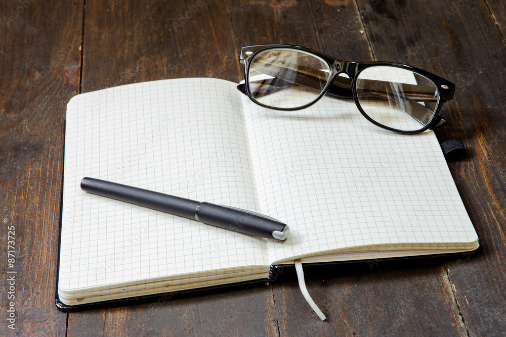 Reading glasses and notepad on wooden background Reading glasses and notepad on wooden background