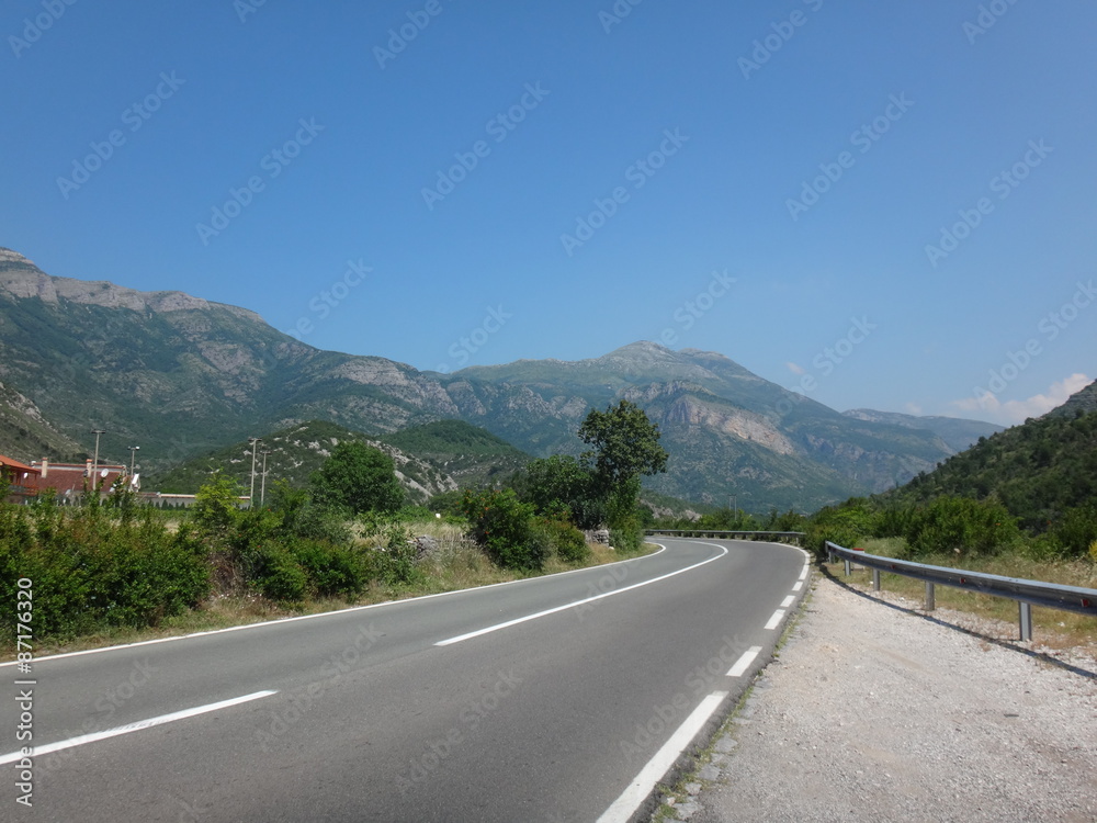 Naklejka premium Дорога трасса в горахгорах летним днем в окружении зелени