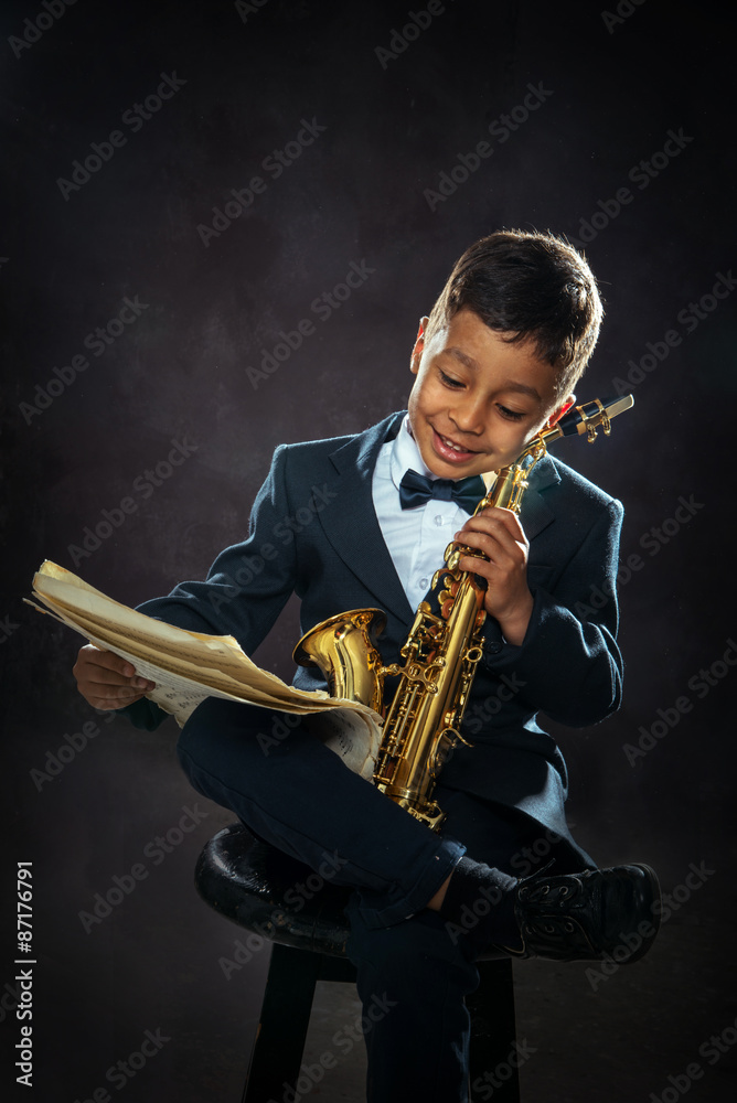 Naklejka premium six years old boy sit with saxophone
