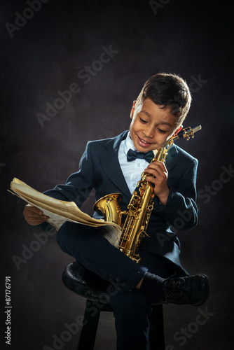 six years old boy sit with saxophone
