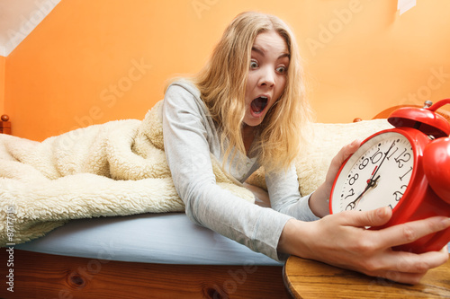 Woman waking up late turning off alarm clock.
