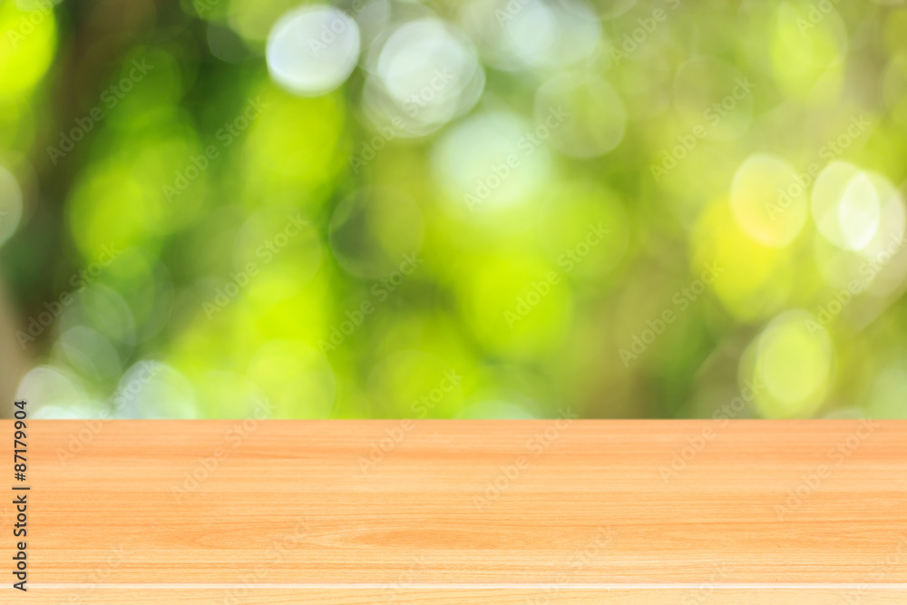 Top wooden table with sunny abstract green nature background, bl Top wooden table with sunny abstract green nature background, bl