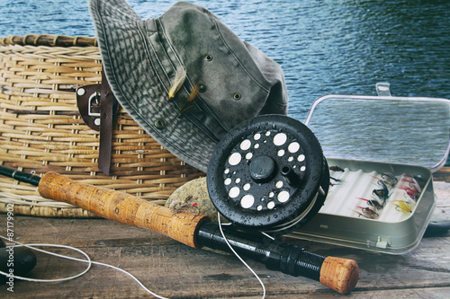 Hat and fly fishing gear on table near the water