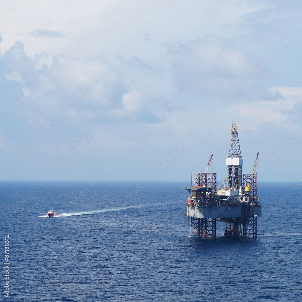 Jack up drilling rig and crew boat in the middle of the sea Jack up drilling rig and crew boat in the middle of the sea
