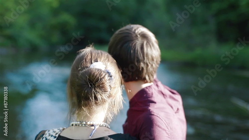 Backside view of a young couple observing summer landscape near the river. Close-up photo