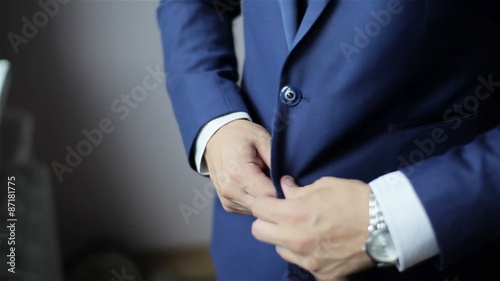 Buttoning a jacket. Stylish man in a suit fastening buttons on his jacket preparing to go out. Close up