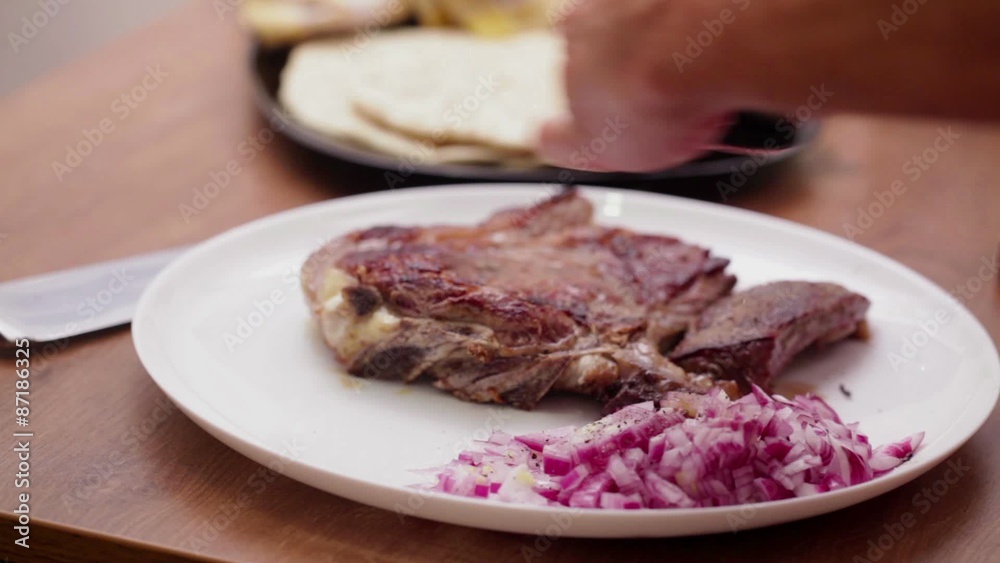 Fresh bone steak seasoned with ground black pepper; close up Fresh bone steak seasoned with ground black pepper; close up