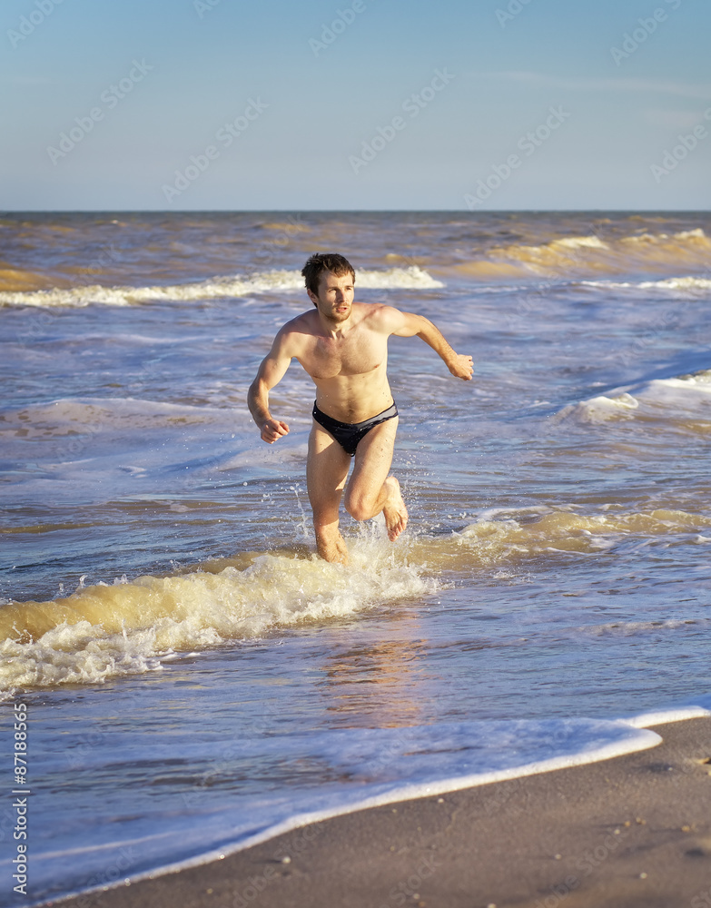 Fototapeta premium Athletic Man Running in water on Beach