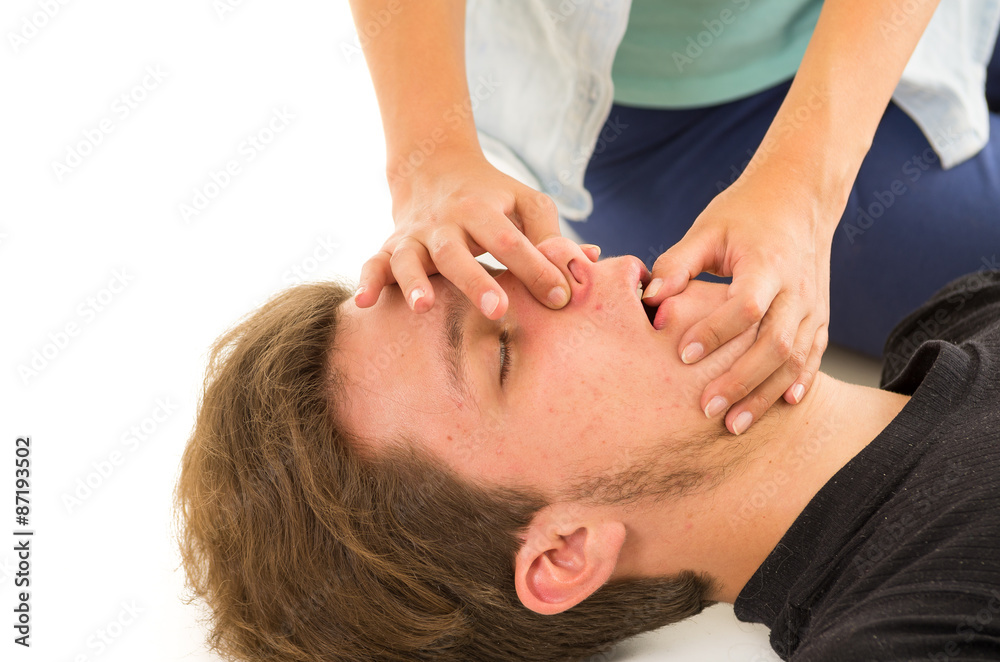 Couple demonstrating first aid techniques with female hand holding male patients nose and other finger in males mouth