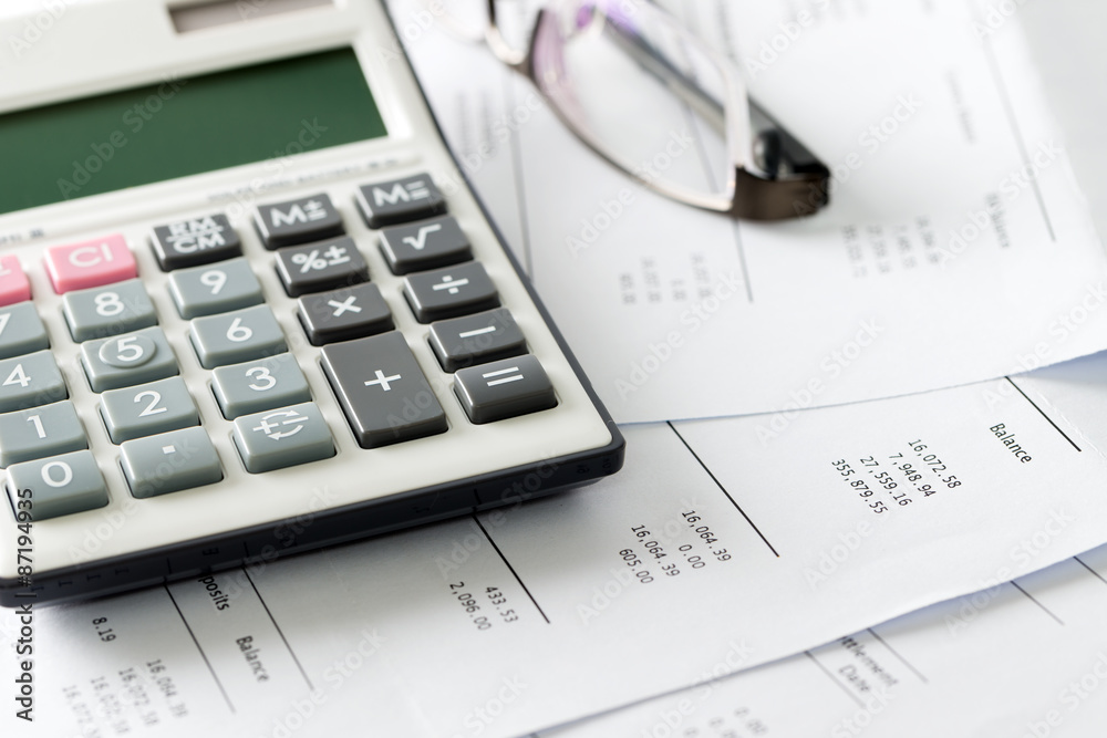 Financial statement with calculator and glasses Financial statement with calculator and glasses