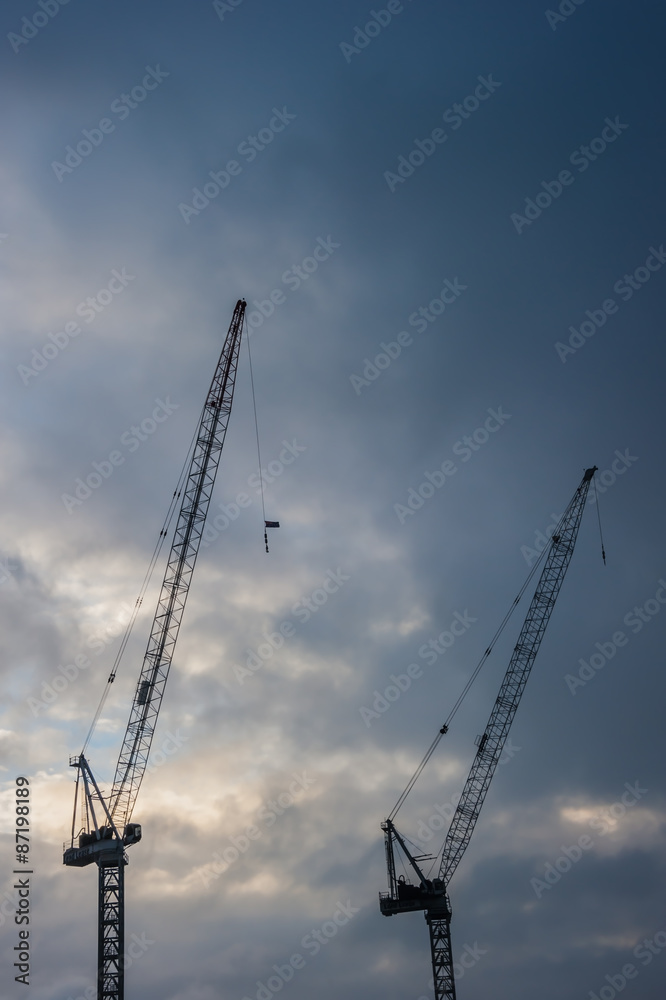 Industrial construction cranes  silhouettes before rain storm.
