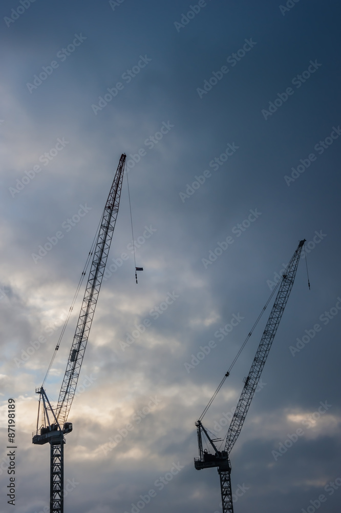 Industrial construction cranes silhouettes before rain storm. Industrial construction cranes silhouettes before rain storm.