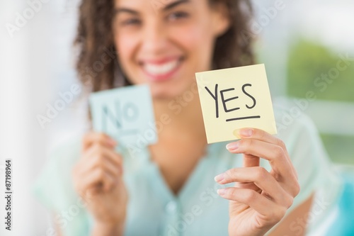 Smiling businesswoman holding yes and no sticks photo