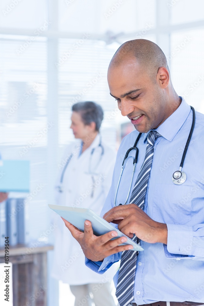 Smiling doctor using his tablet Smiling doctor using his tablet