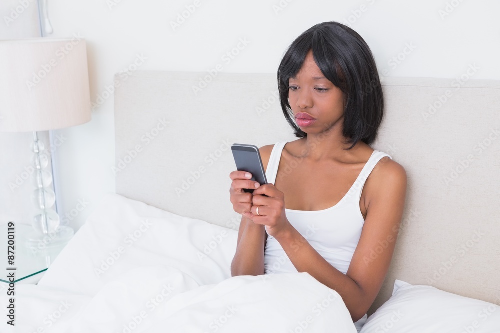 Pretty brunette woman using her mobile phone in her bed Pretty brunette woman using her mobile phone in her bed