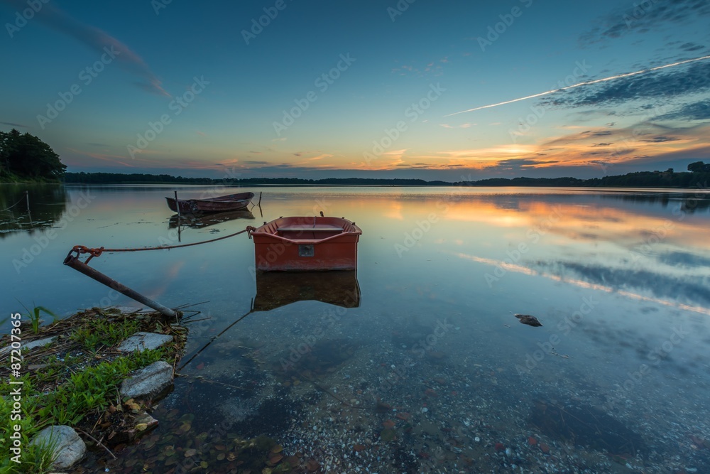 Obraz premium Beautiful lake sunset with fisherman boat