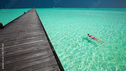 Young woman swimming in a coral lagoon next to jetty photo