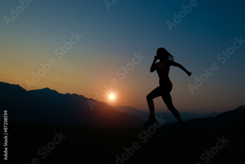 Silhouette of woman running at sunset in the mountains
