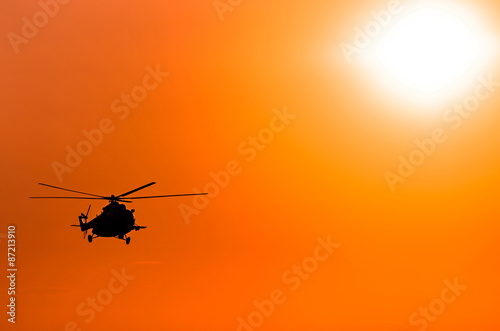 transport helicopter silhouette against a red sky © balakleypb