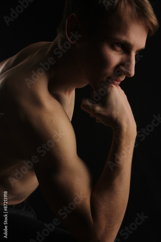 the handsome strong serious nude young man a hand at a chin