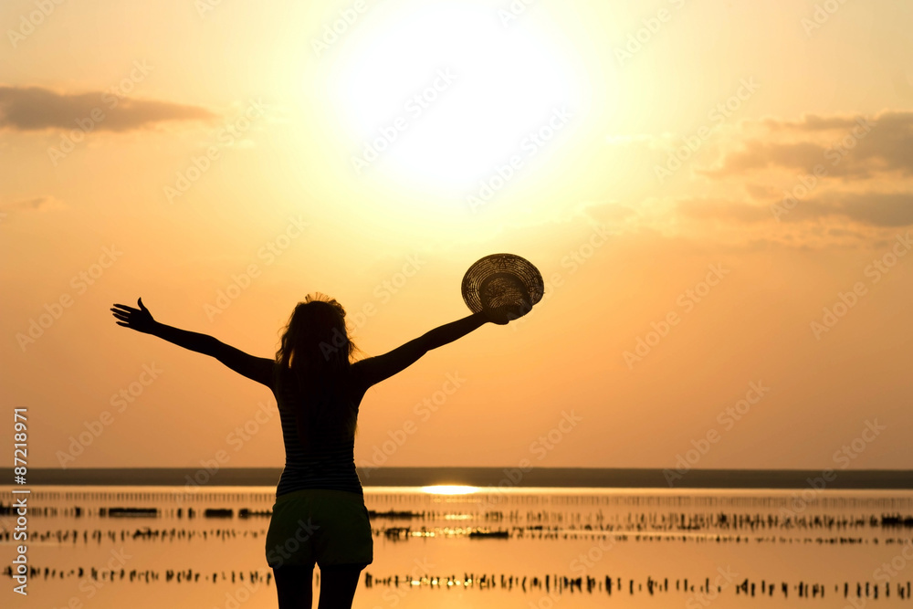 Fototapeta premium silhouette of a young girl on the sea in a hat
