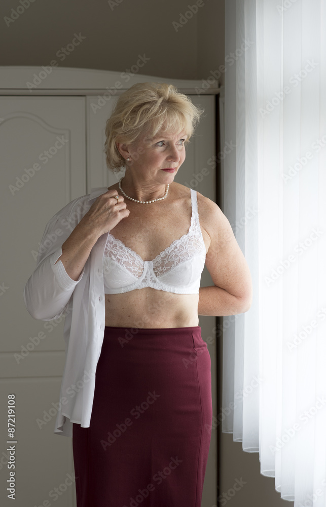Elderly woman getting dressed putting on a white shirt Stock Photo Adobe Stock