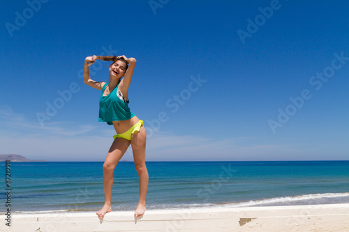 Brunette teen in bikini and beachwear enjoys the summer sun.