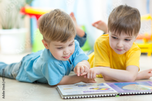Two boys reading a book tog...