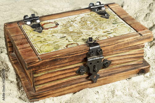 Wooden chest with a map on its cover, on the sand photo