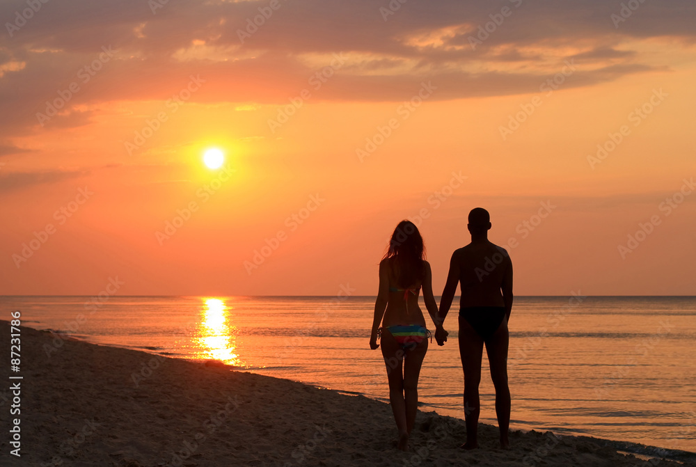 couple silhouette holding hands on the beach at sunrise