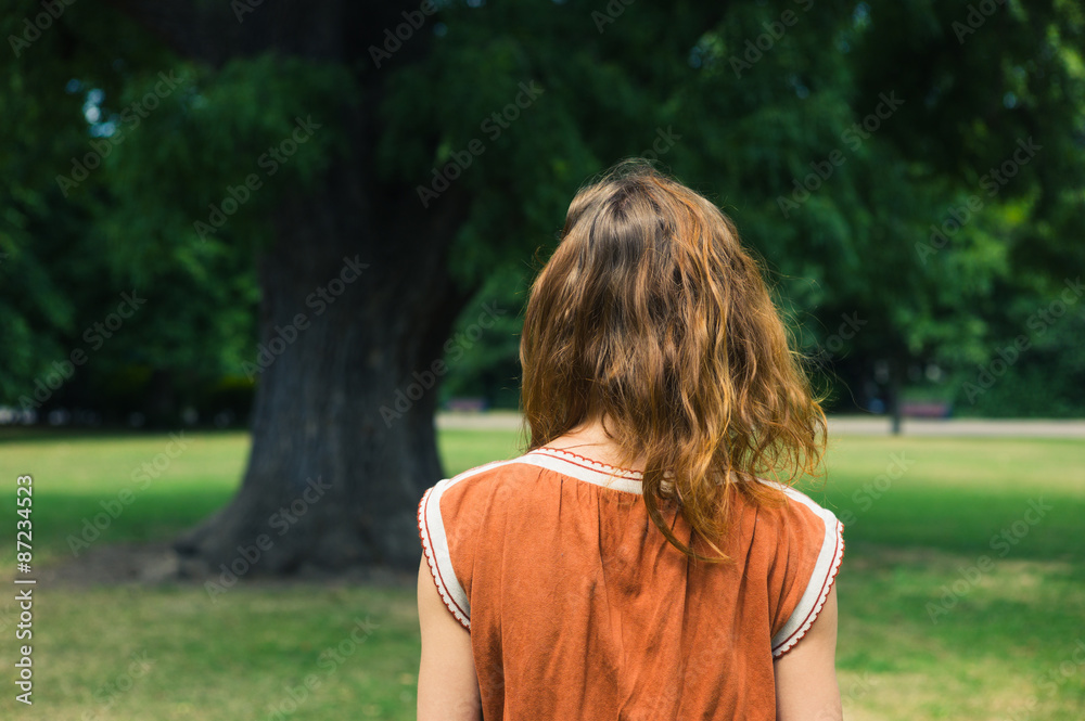 Young woman looking at tree in park
