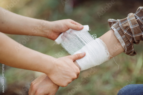 A person wrapping his friends arm in gauze