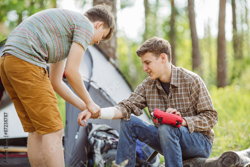 A person wrapping his friends arm in gauze