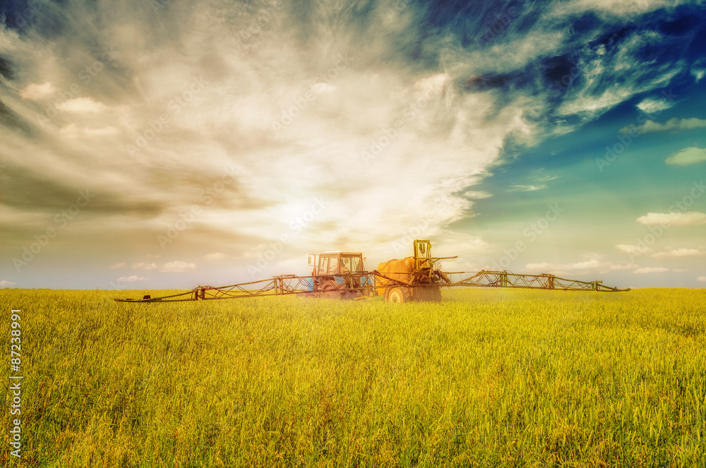 Fototapeta premium Farming tractor spraying green field